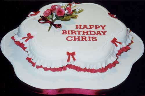 A modern petal-shaped rich fruit cake with burgundy and white sugar crafted flowers, frills and bows.