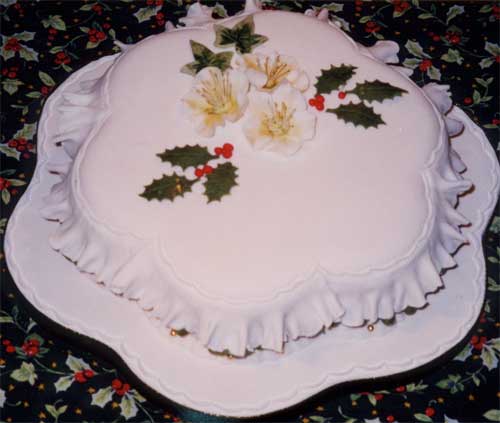 A Christmas cake decorated with holly and Christmas roses.